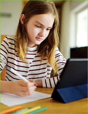 Girl doing schoolwork at home with digital tablet